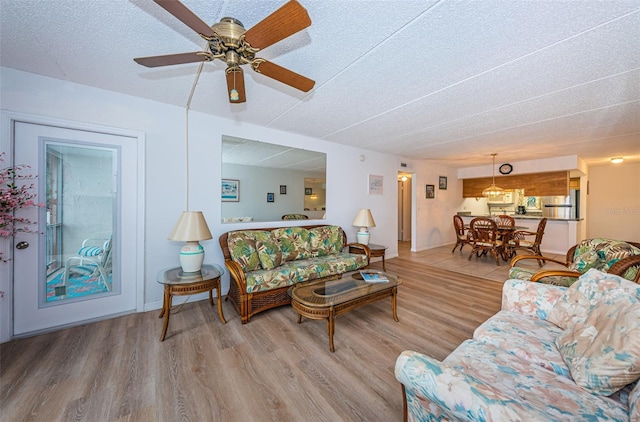 living room with hardwood / wood-style flooring, ceiling fan, and a textured ceiling