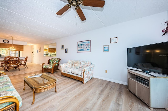 living room featuring a textured ceiling, light wood-type flooring, and ceiling fan