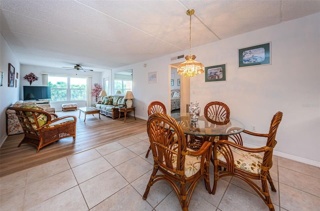 tiled dining space featuring a textured ceiling and ceiling fan with notable chandelier