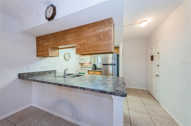 kitchen featuring white appliances, sink, a textured ceiling, light tile patterned flooring, and kitchen peninsula