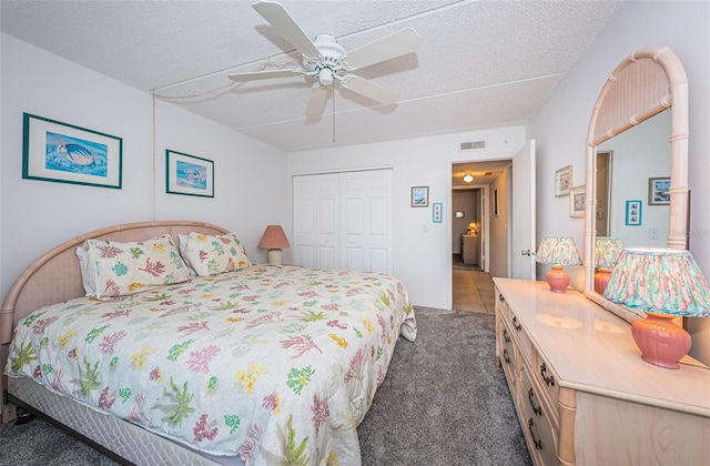 bedroom with ceiling fan, a closet, dark carpet, and a textured ceiling