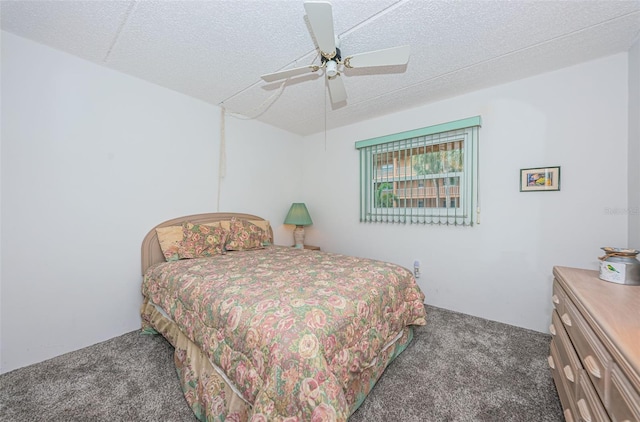 bedroom featuring ceiling fan, a textured ceiling, and dark colored carpet