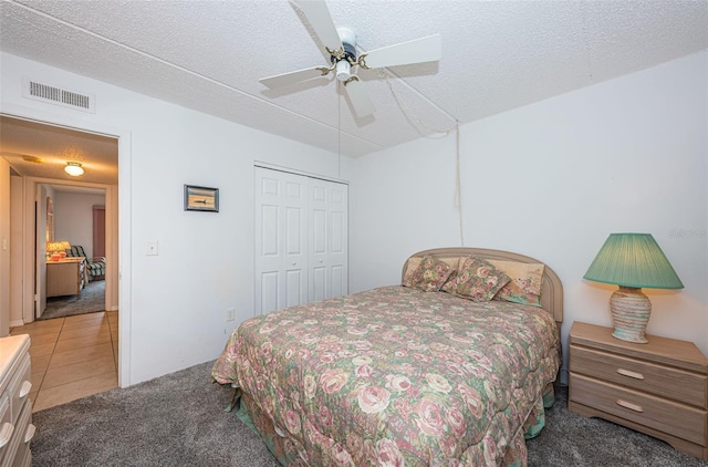 bedroom featuring a textured ceiling, a closet, tile patterned floors, and ceiling fan