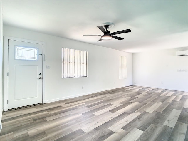 foyer entrance with ceiling fan, a wall unit AC, and light hardwood / wood-style flooring