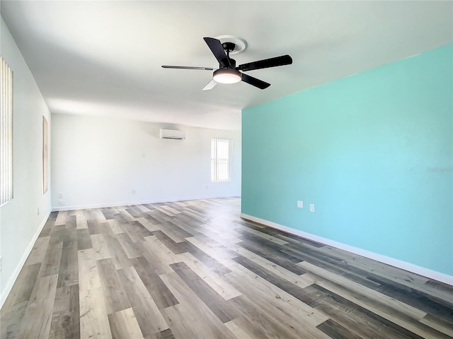 unfurnished room featuring a wall unit AC, ceiling fan, and wood-type flooring