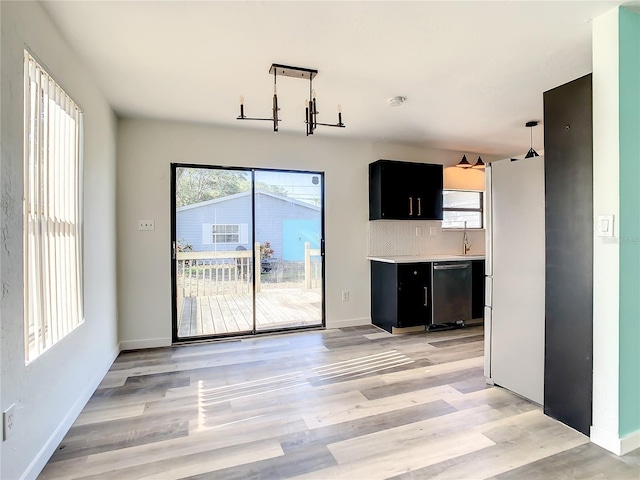 kitchen featuring black dishwasher, tasteful backsplash, white fridge, light hardwood / wood-style floors, and decorative light fixtures