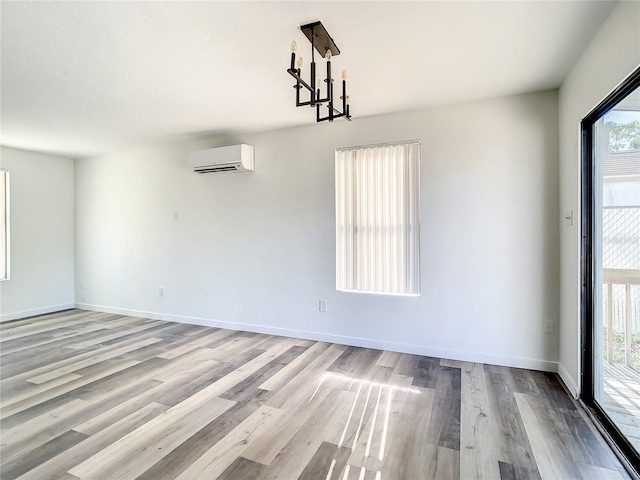 unfurnished dining area featuring a chandelier, light hardwood / wood-style flooring, and a wall unit AC