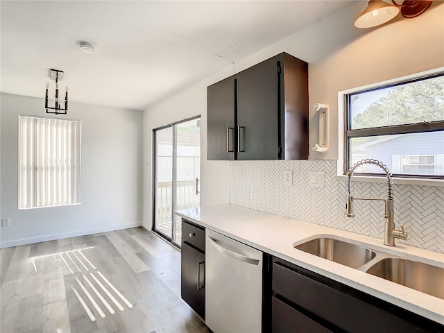 kitchen with decorative backsplash, stainless steel dishwasher, sink, light hardwood / wood-style floors, and hanging light fixtures