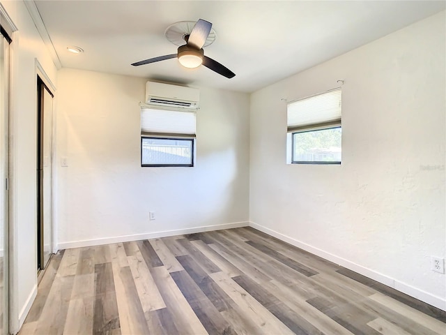 unfurnished bedroom with ceiling fan, light wood-type flooring, and a wall mounted AC