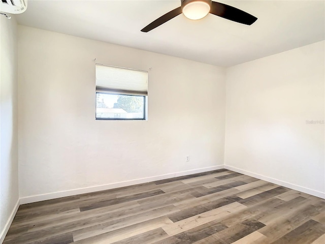 empty room featuring a wall mounted air conditioner, ceiling fan, and wood-type flooring