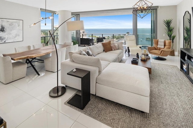 living area featuring a healthy amount of sunlight, a water view, light tile patterned flooring, and an inviting chandelier