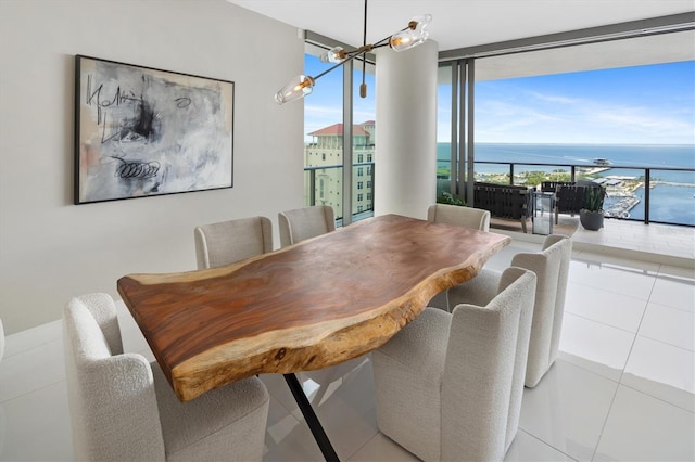 tiled dining area featuring a notable chandelier, floor to ceiling windows, and a water view