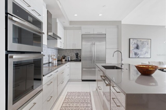 kitchen with sink, stainless steel appliances, white cabinets, decorative backsplash, and wall chimney exhaust hood