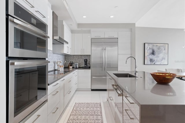 kitchen featuring stainless steel appliances, white cabinets, wall chimney range hood, and modern cabinets