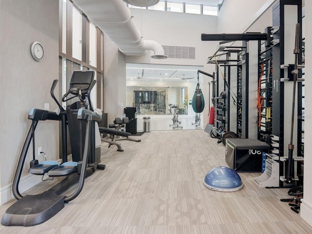 exercise room featuring light colored carpet and a high ceiling