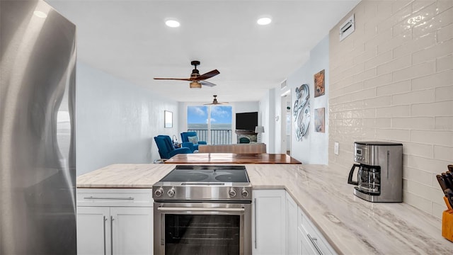 kitchen featuring ceiling fan, appliances with stainless steel finishes, white cabinets, and light stone counters