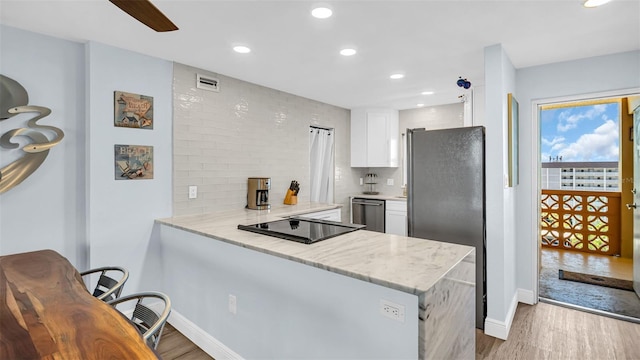 kitchen featuring decorative backsplash, white cabinetry, appliances with stainless steel finishes, and kitchen peninsula