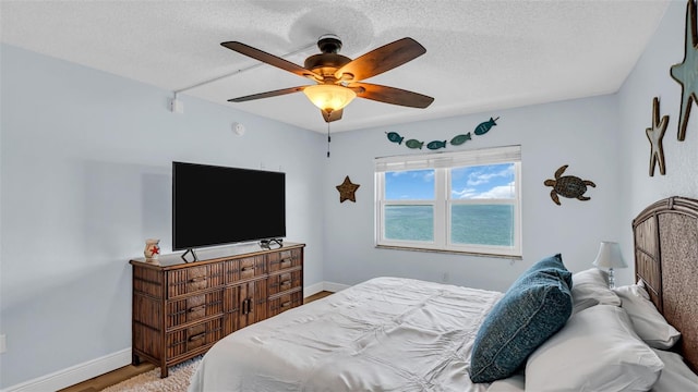 bedroom featuring ceiling fan, a textured ceiling, and light hardwood / wood-style floors