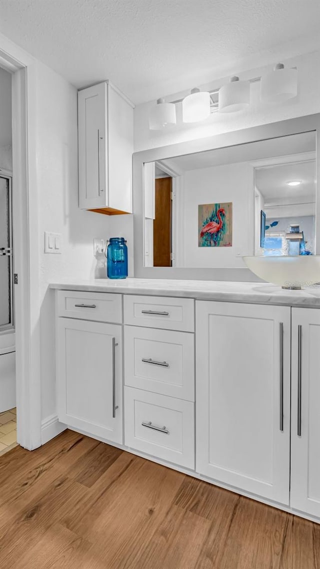 bathroom featuring a textured ceiling, wood-type flooring, vanity, and an enclosed shower