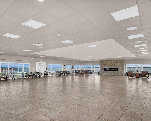 gym with a paneled ceiling and a fireplace