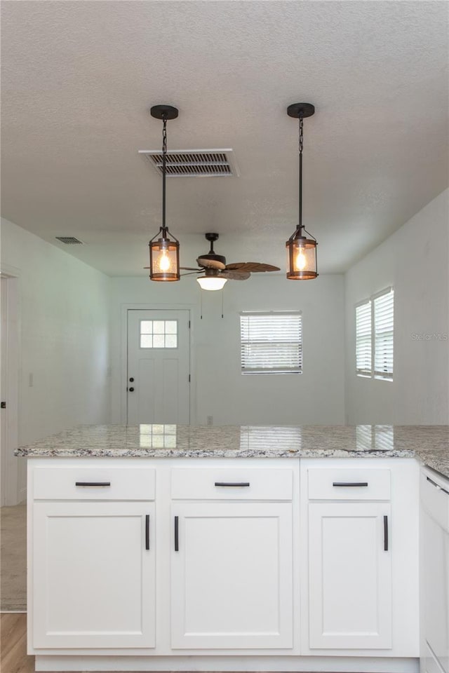 kitchen with white dishwasher, ceiling fan, light hardwood / wood-style flooring, white cabinets, and hanging light fixtures