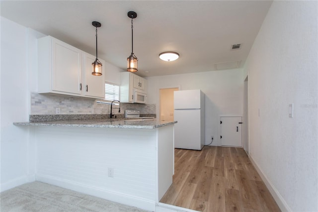 kitchen with kitchen peninsula, light stone countertops, light wood-type flooring, white appliances, and white cabinetry