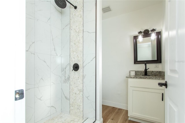 bathroom featuring vanity, wood-type flooring, and tiled shower