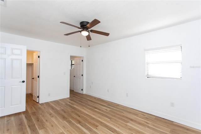 unfurnished bedroom featuring a walk in closet, light hardwood / wood-style floors, and ceiling fan