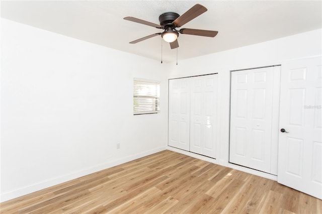 unfurnished bedroom featuring ceiling fan, light hardwood / wood-style flooring, and two closets