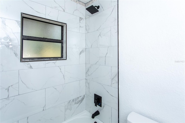 bathroom with toilet and tiled shower / bath