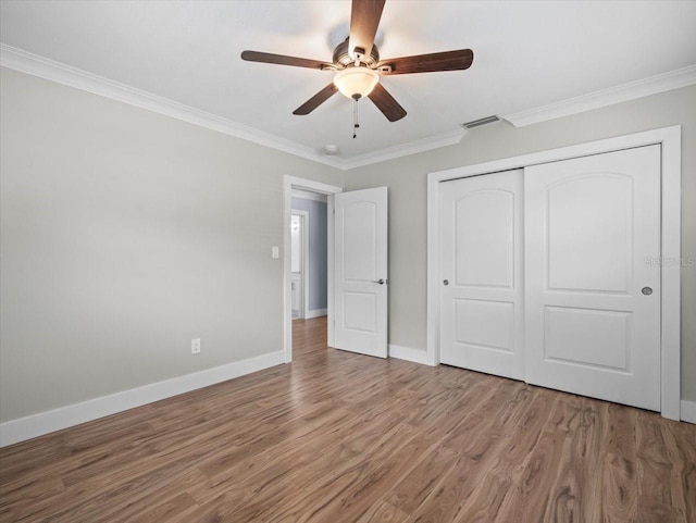 unfurnished bedroom featuring hardwood / wood-style floors, crown molding, a closet, and ceiling fan