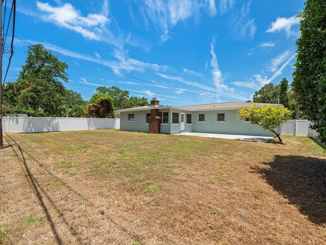 rear view of house with a lawn and a patio