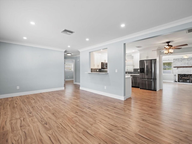 unfurnished living room with ceiling fan, ornamental molding, a fireplace, and light hardwood / wood-style floors