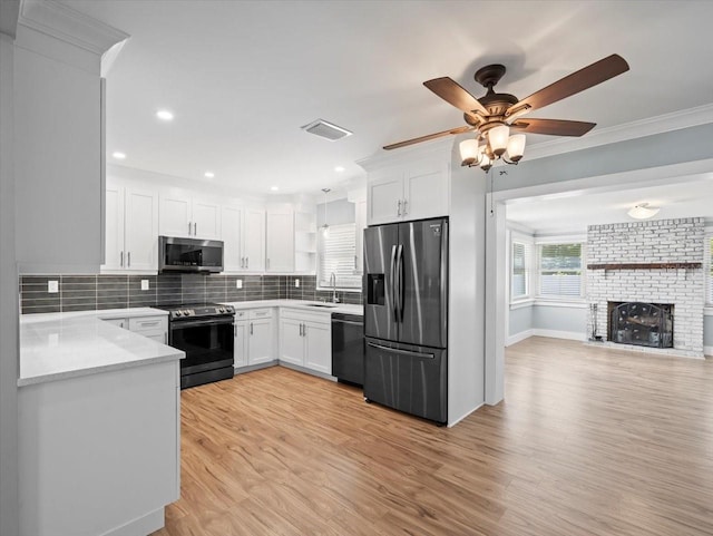 kitchen with appliances with stainless steel finishes, white cabinetry, sink, decorative backsplash, and light wood-type flooring