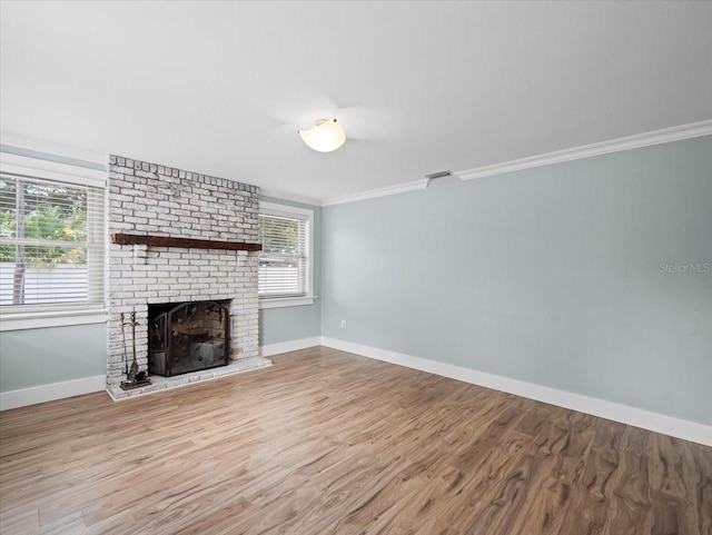 unfurnished living room with ornamental molding, light hardwood / wood-style floors, and a brick fireplace