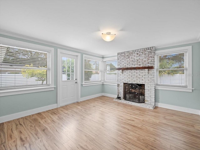 unfurnished living room featuring a fireplace, crown molding, light hardwood / wood-style flooring, and a healthy amount of sunlight