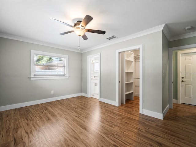 unfurnished bedroom featuring crown molding, dark hardwood / wood-style floors, ensuite bathroom, a walk in closet, and a closet