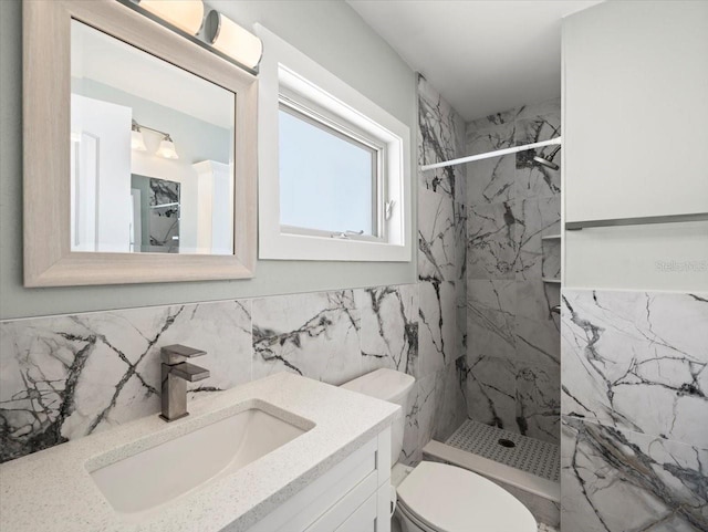 bathroom featuring tiled shower, vanity, toilet, and tile walls