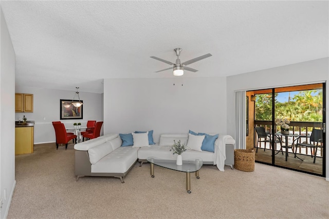 living room with ceiling fan, light colored carpet, and a textured ceiling