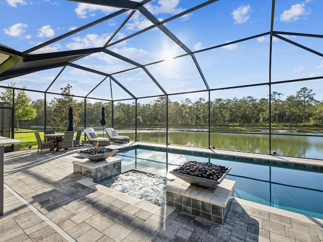 view of swimming pool with glass enclosure, a patio area, and a water view