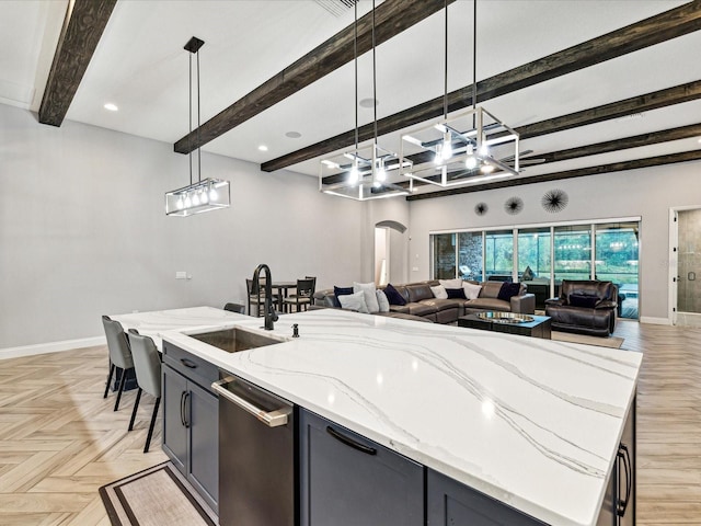 kitchen with pendant lighting, light stone countertops, an island with sink, and light parquet flooring