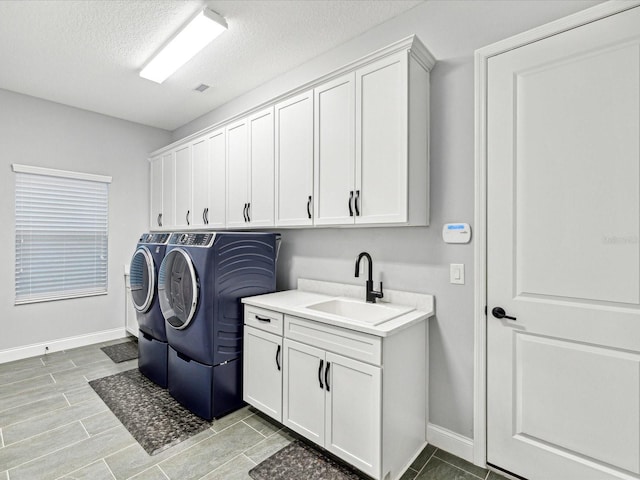 laundry room featuring a textured ceiling, cabinets, independent washer and dryer, and sink