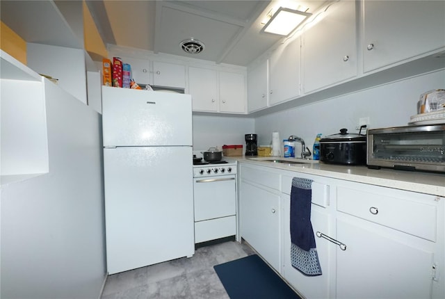 kitchen with white appliances, a toaster, light countertops, white cabinetry, and a sink