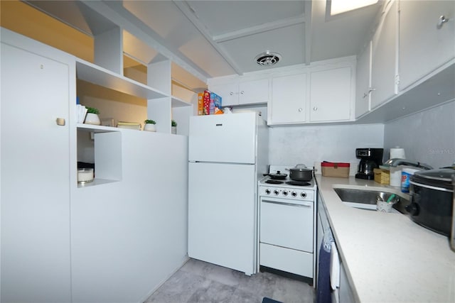 kitchen with light countertops, visible vents, white cabinets, a sink, and white appliances