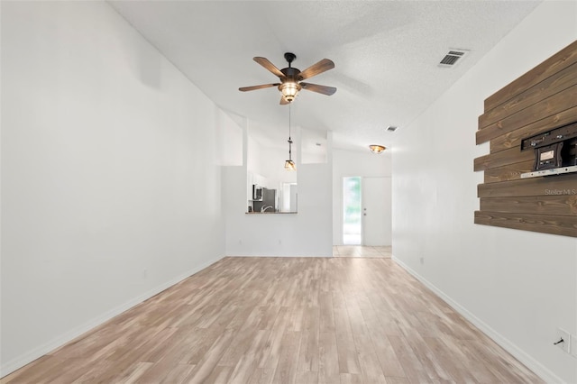 unfurnished living room with ceiling fan, light hardwood / wood-style floors, lofted ceiling, and a textured ceiling