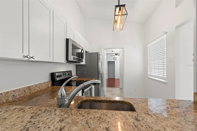 kitchen featuring appliances with stainless steel finishes, light stone counters, sink, pendant lighting, and white cabinets