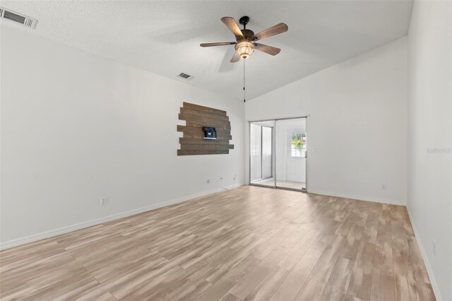 empty room with ceiling fan, light hardwood / wood-style floors, a textured ceiling, and high vaulted ceiling