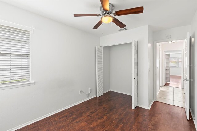 unfurnished bedroom with ceiling fan, dark wood-type flooring, and a closet