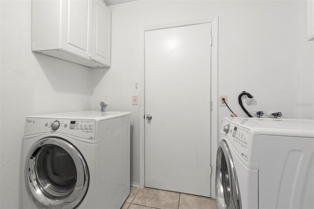 laundry area with cabinets, light tile patterned floors, and washing machine and clothes dryer