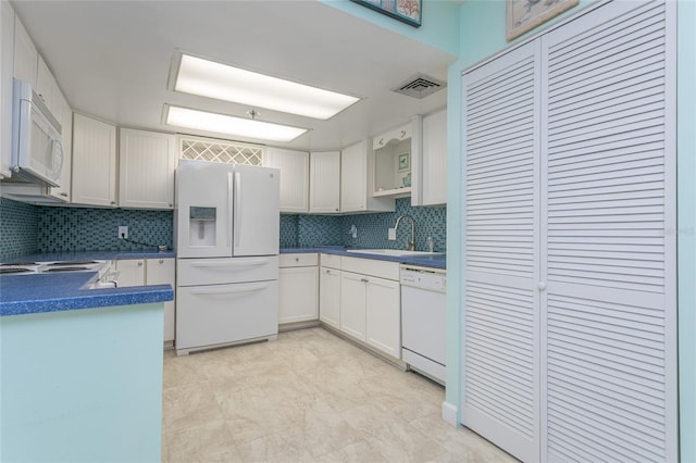 kitchen featuring sink, backsplash, white cabinets, and white appliances